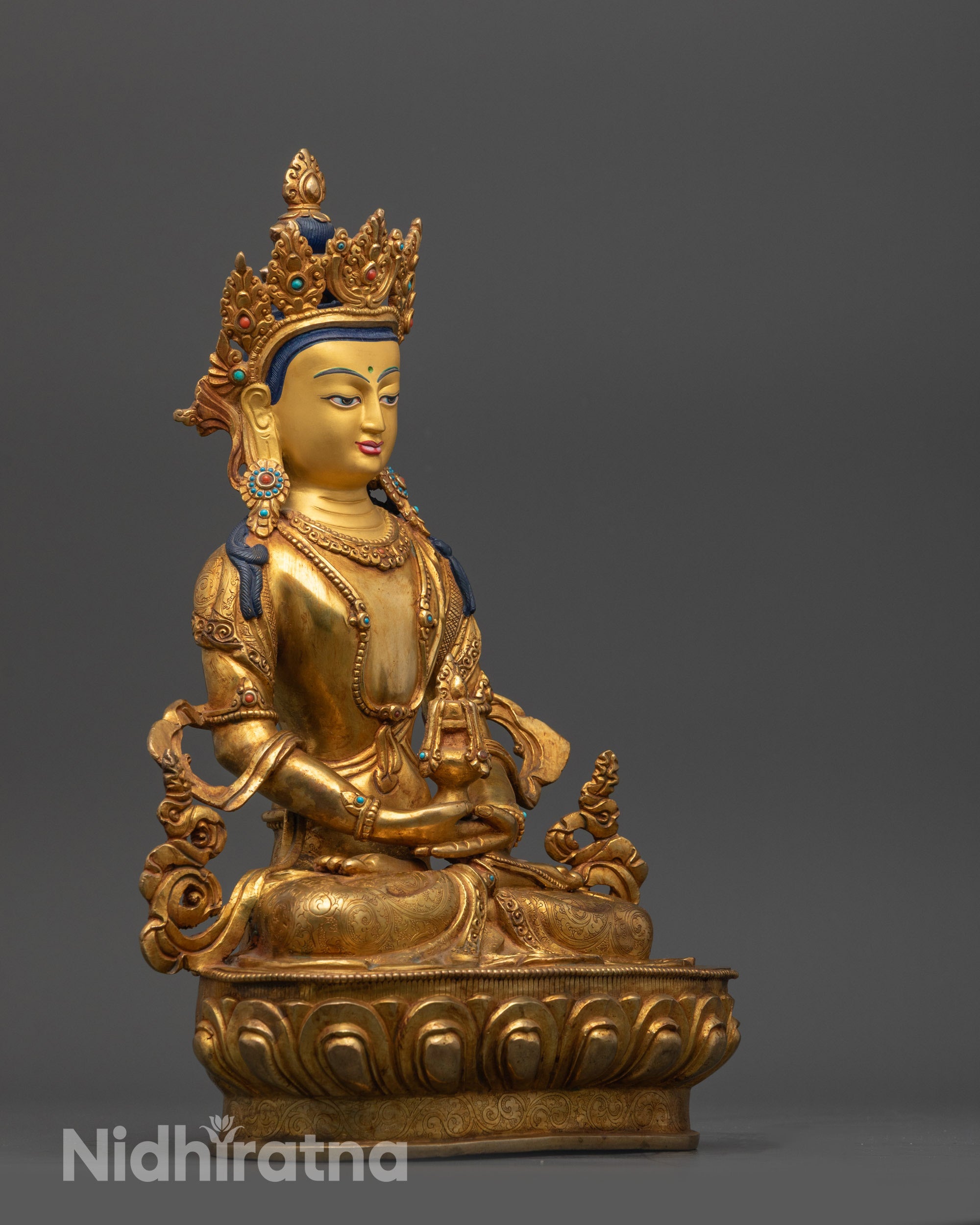 Side view Amitayus Statue adorned with crown and detailed flowing robes on copper base
