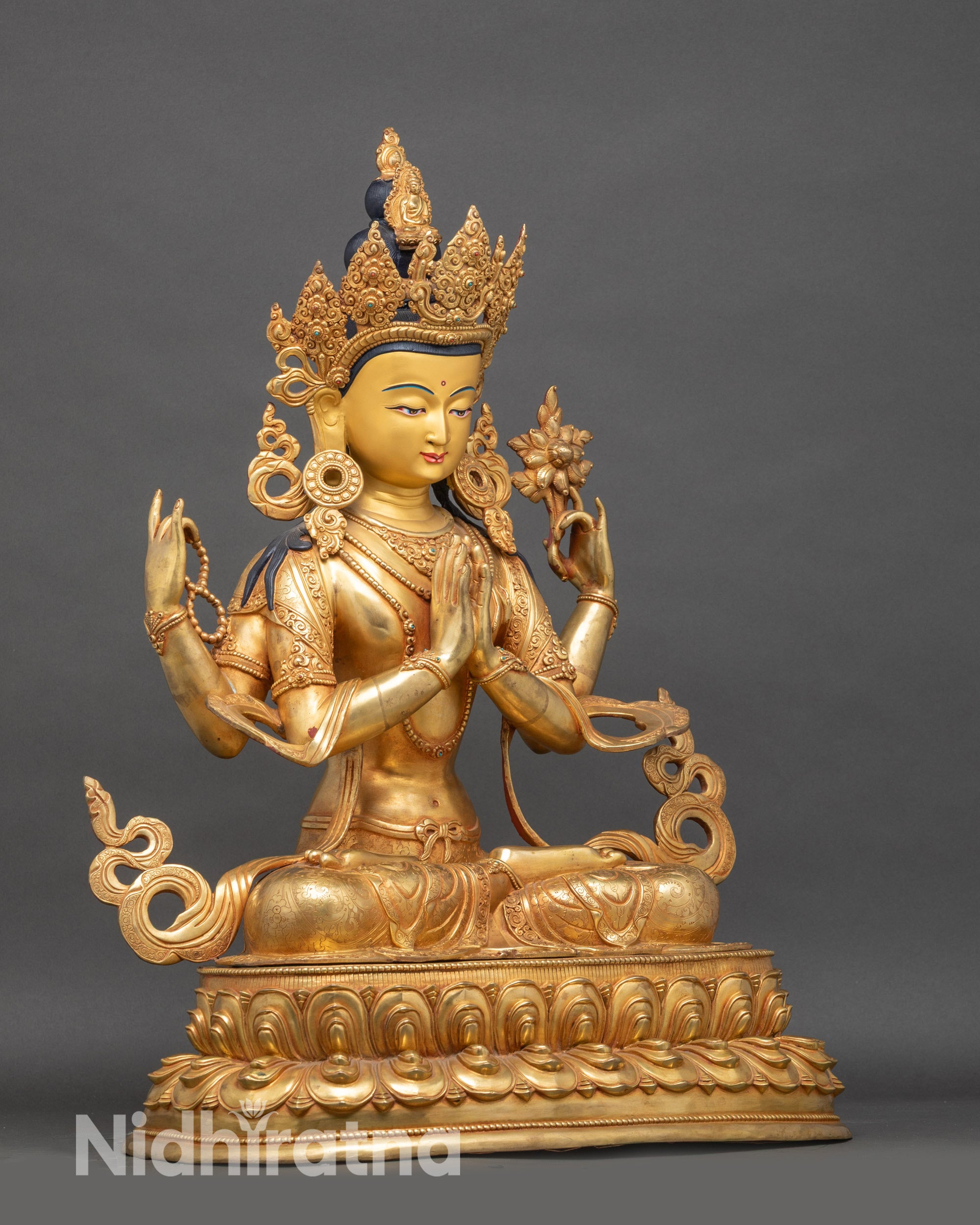 Side view Chenrezig sculpture holding wish-fulfilling jewel and lotus flower