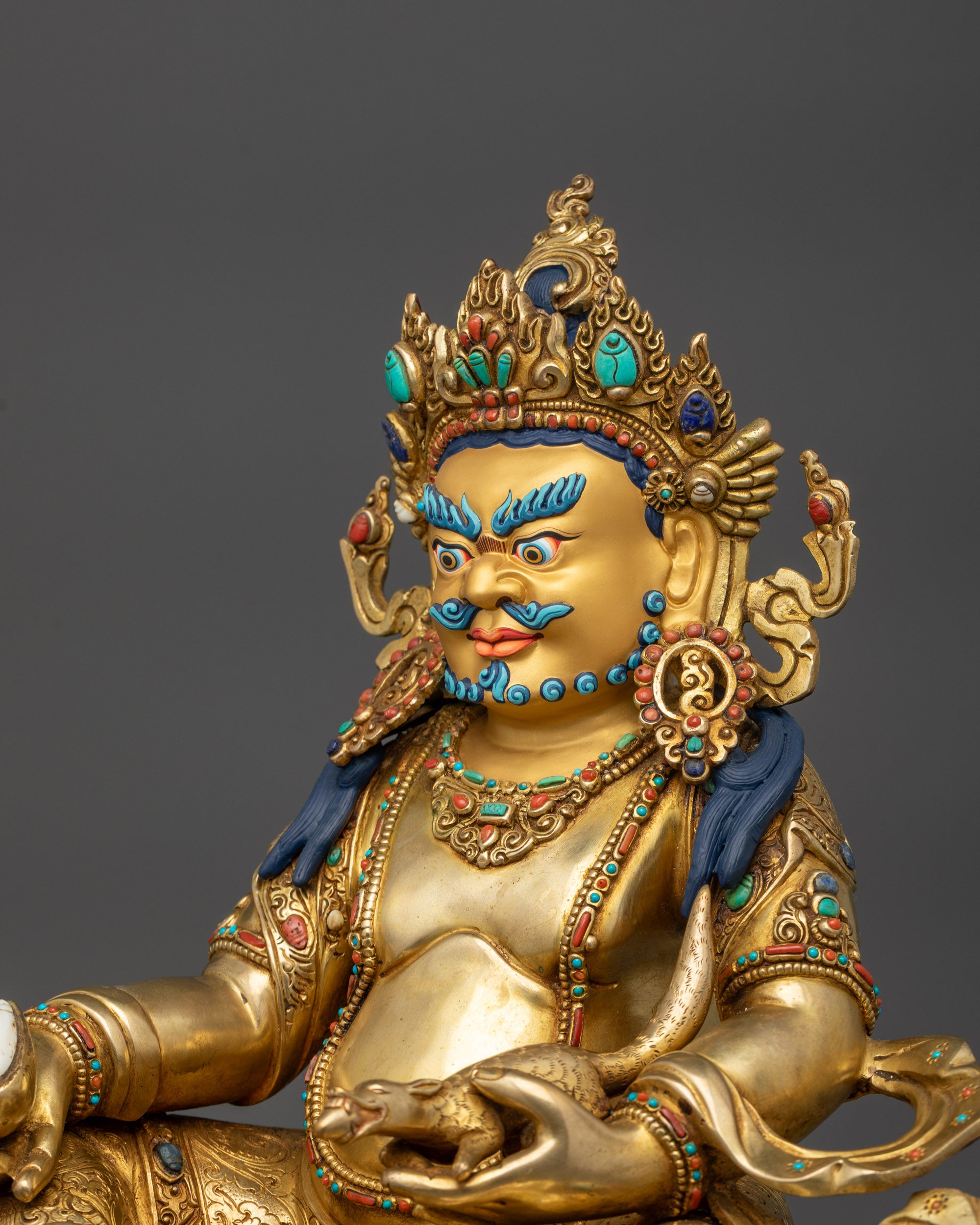 Side view Dzambhala sculpture showing flowing robes and serpent wrapping around body