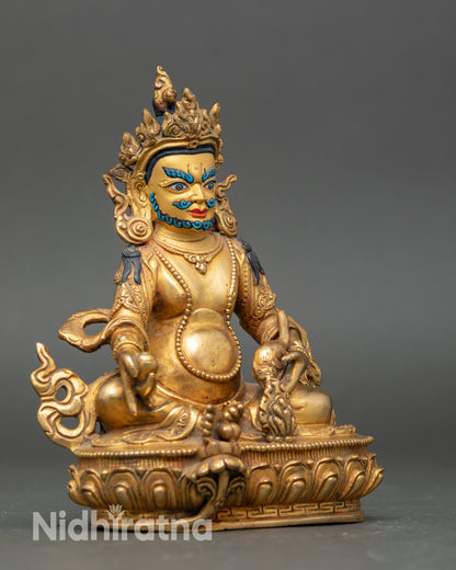 Side view Dzambhala statue on lotus throne holding citron fruits and jewel-spitting mongoose