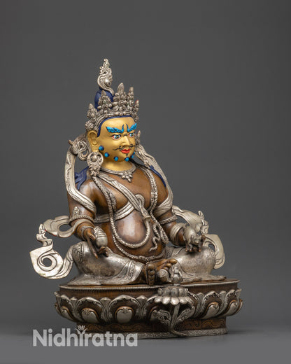 Side view Dzambhala statue seated on lotus with one foot near shell holding citrons and jewels

