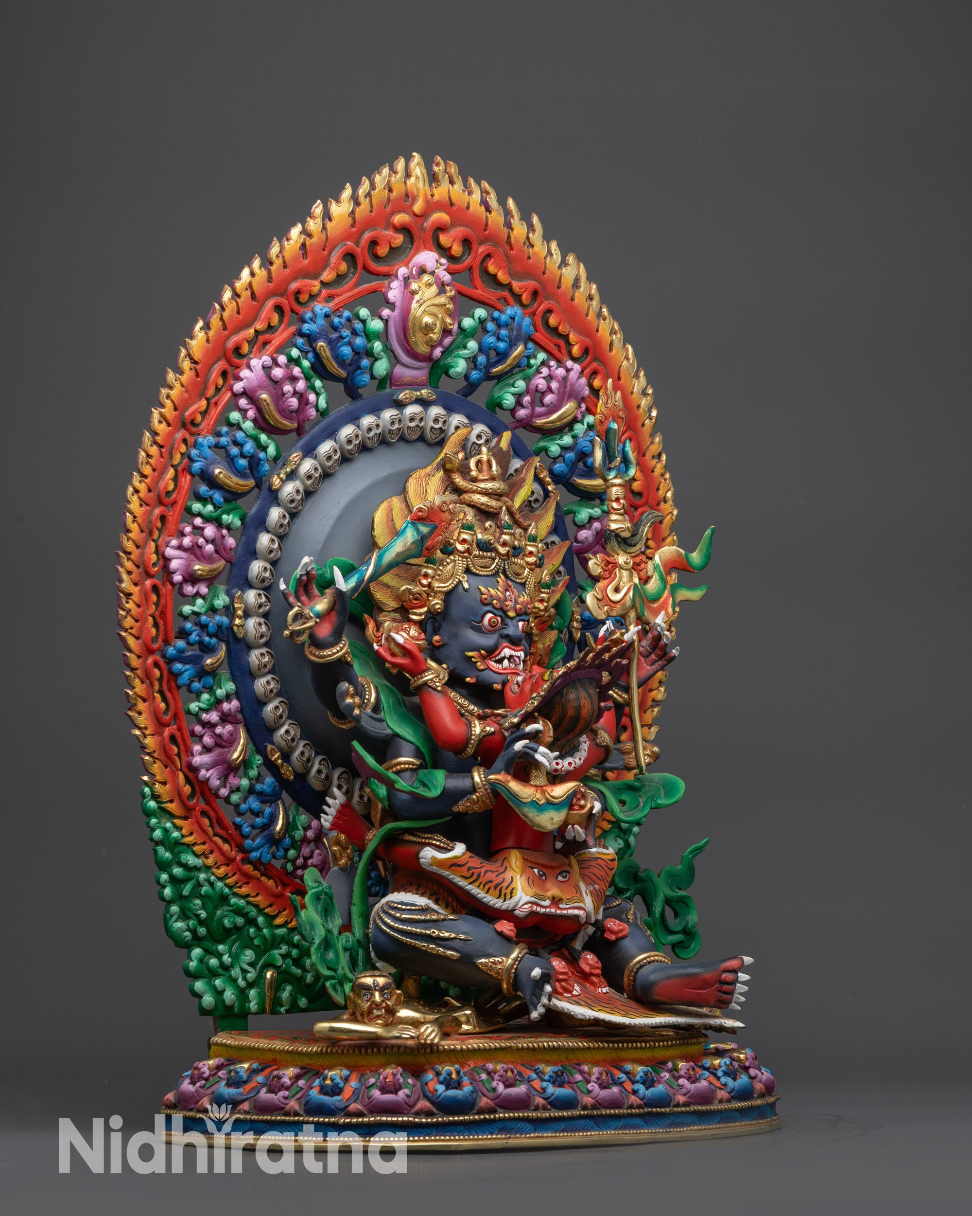 Side view Four-Armed Mahakala Statue holding flaying knife, skull cup, and trident