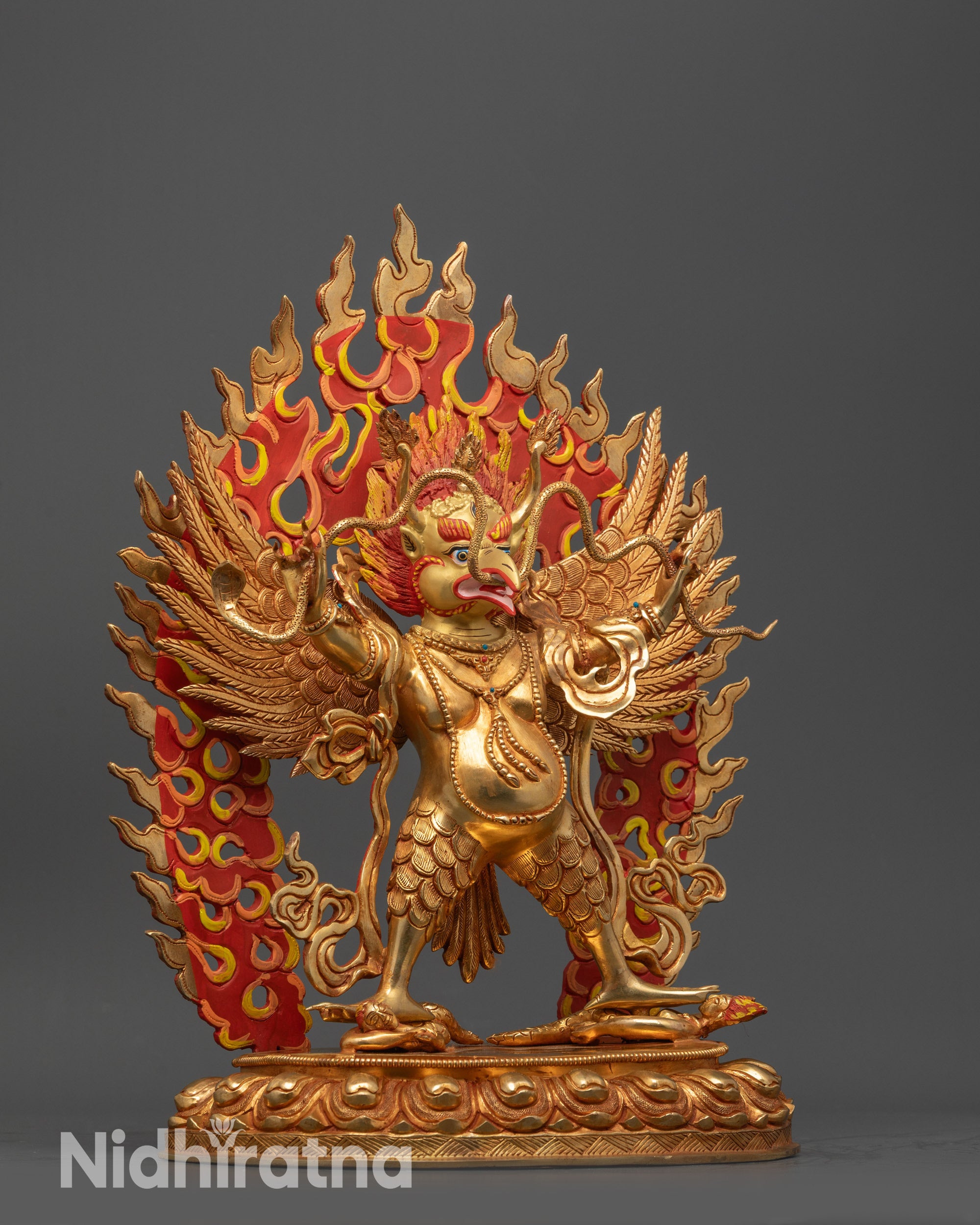 Side view Garuda Dev Statue holding serpent cruising atop subdued evil deities
