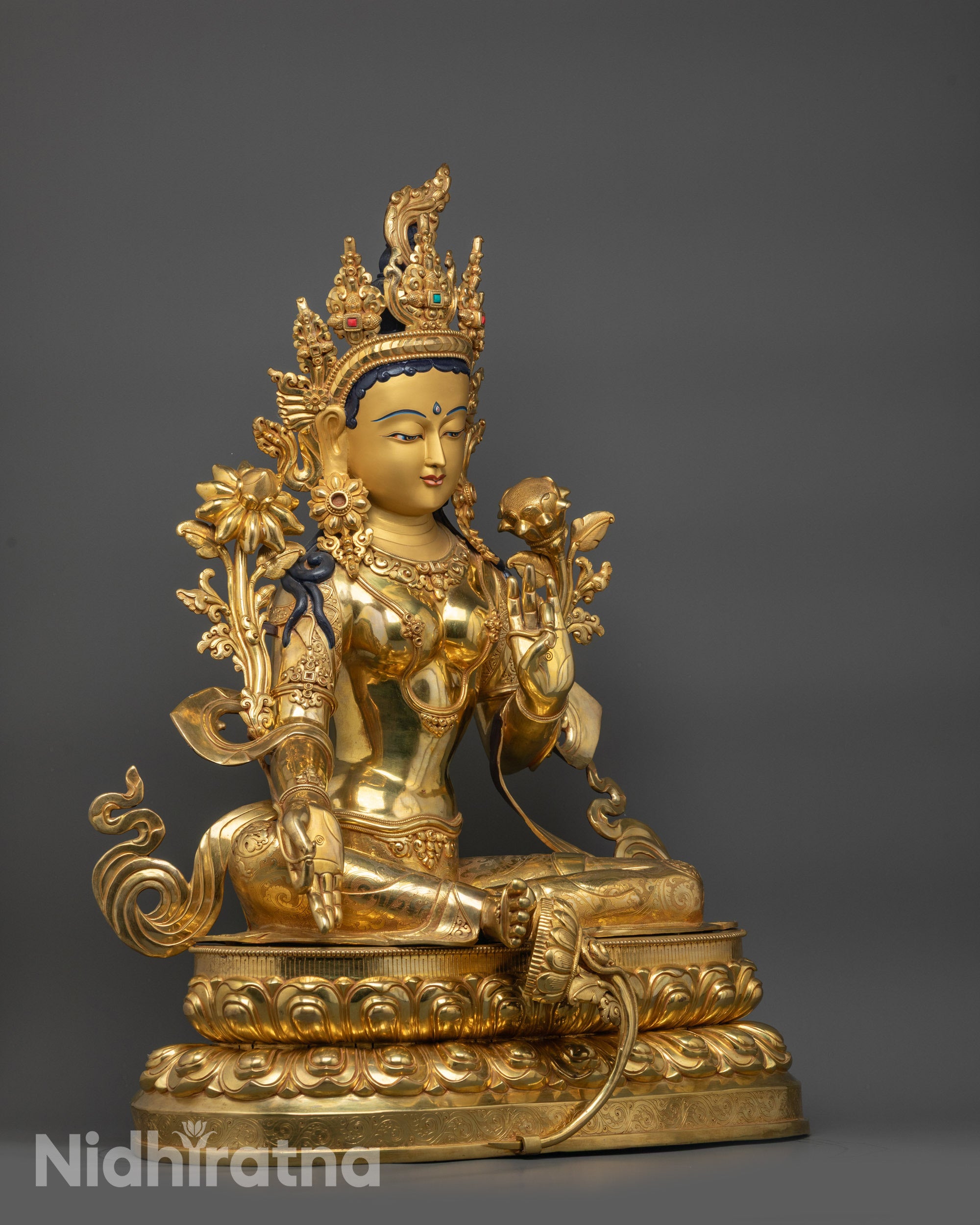 Side view Green Tara Buddhist statue in royal ease pose with glowing copper fire-gilded body