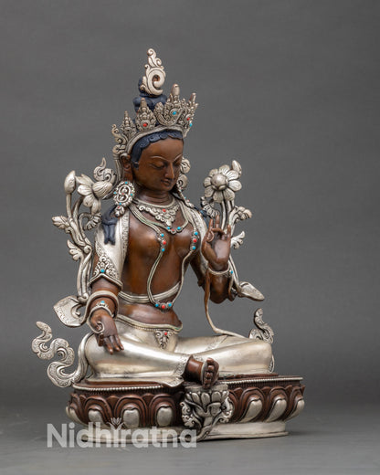 Side view Green Tara sculpture seated on lotus pedestal with extended right leg
