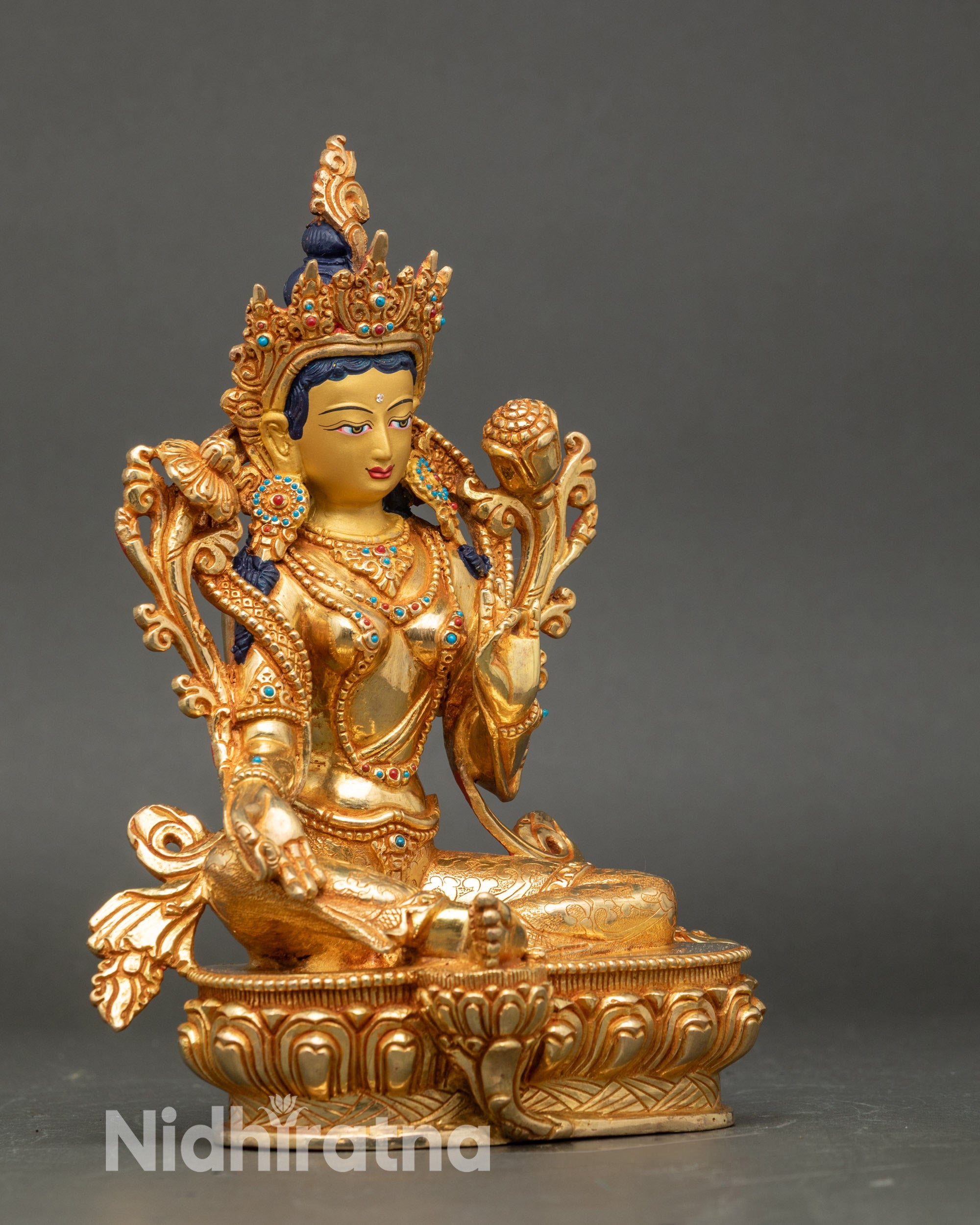 Side view Green Tara seated on lotus throne with flowing robes and ornate jewelry