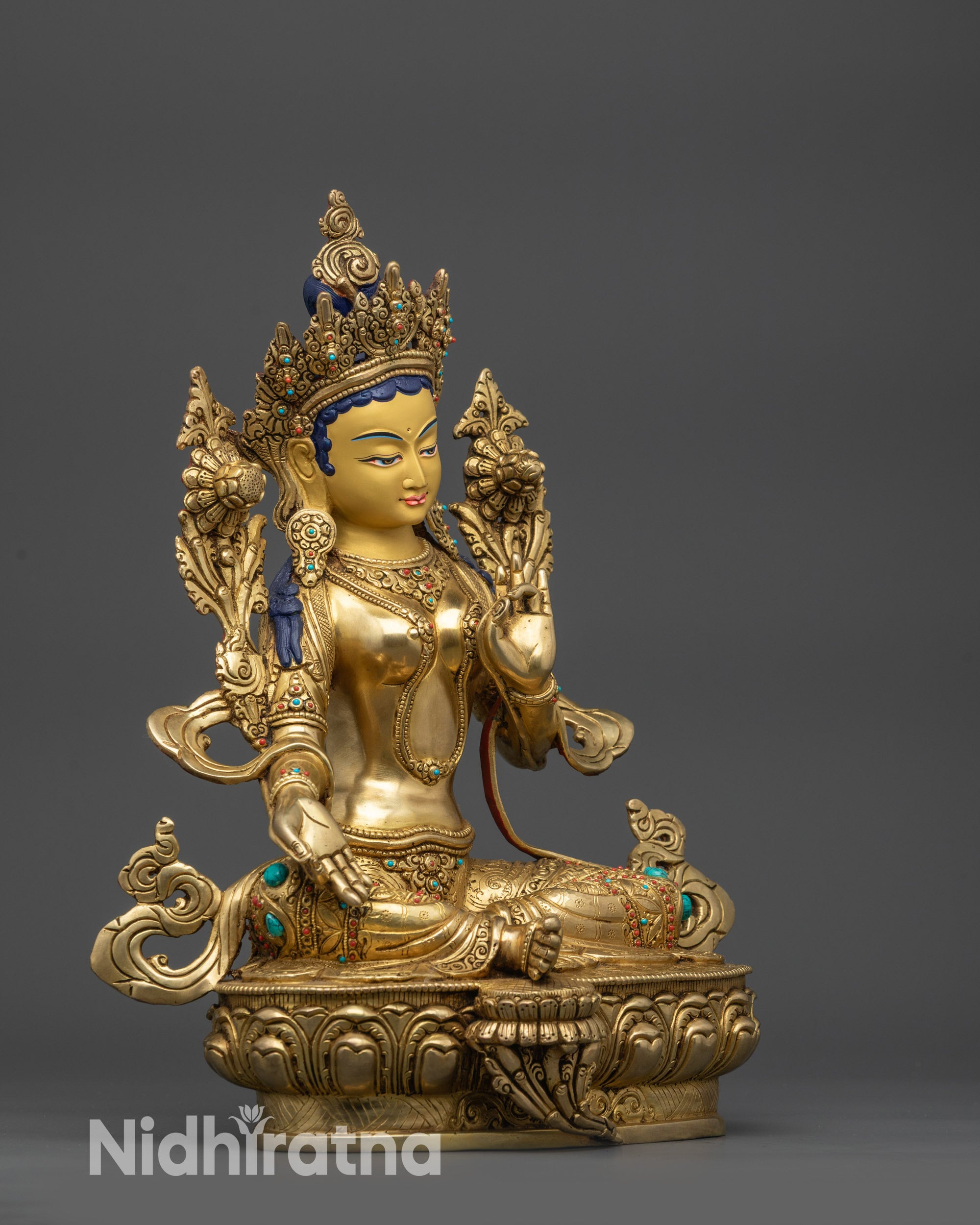 Side view Green Tara statue holding utpala flower with flowing robes detail