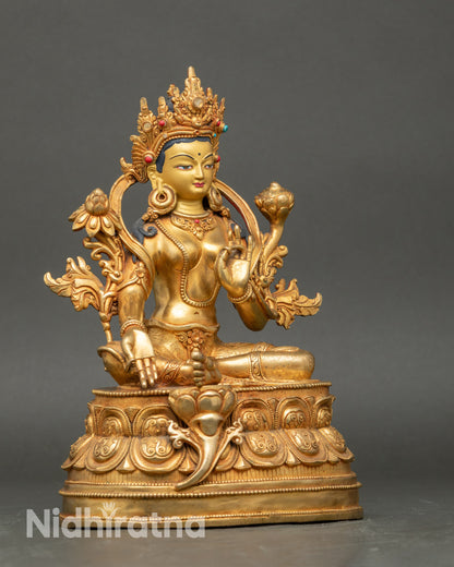 Side view Green Tara statue, right leg extended, Varada and Vitarka mudra, holding Utpala flower