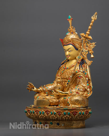 Side view Guru Rinpoche statue holding khatvanga trident with kapala and vajra