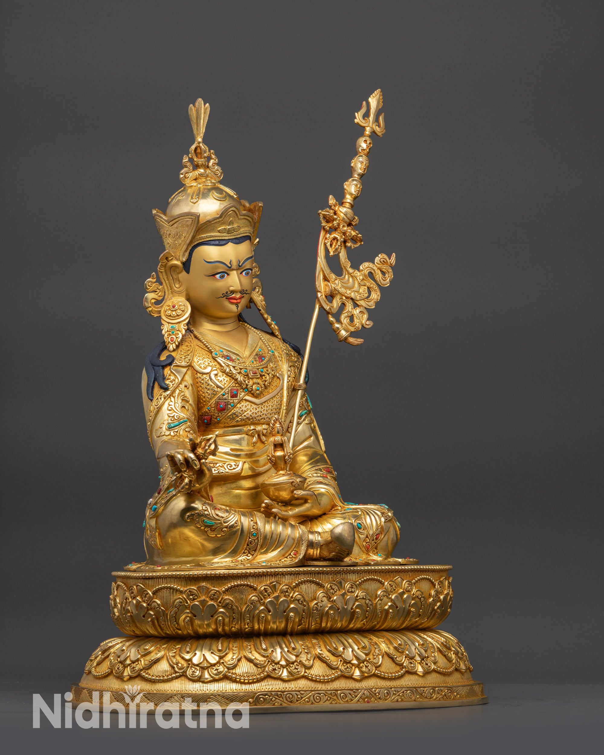Side view Guru Rinpoche statue holding vajra kapala with khatvanga trident