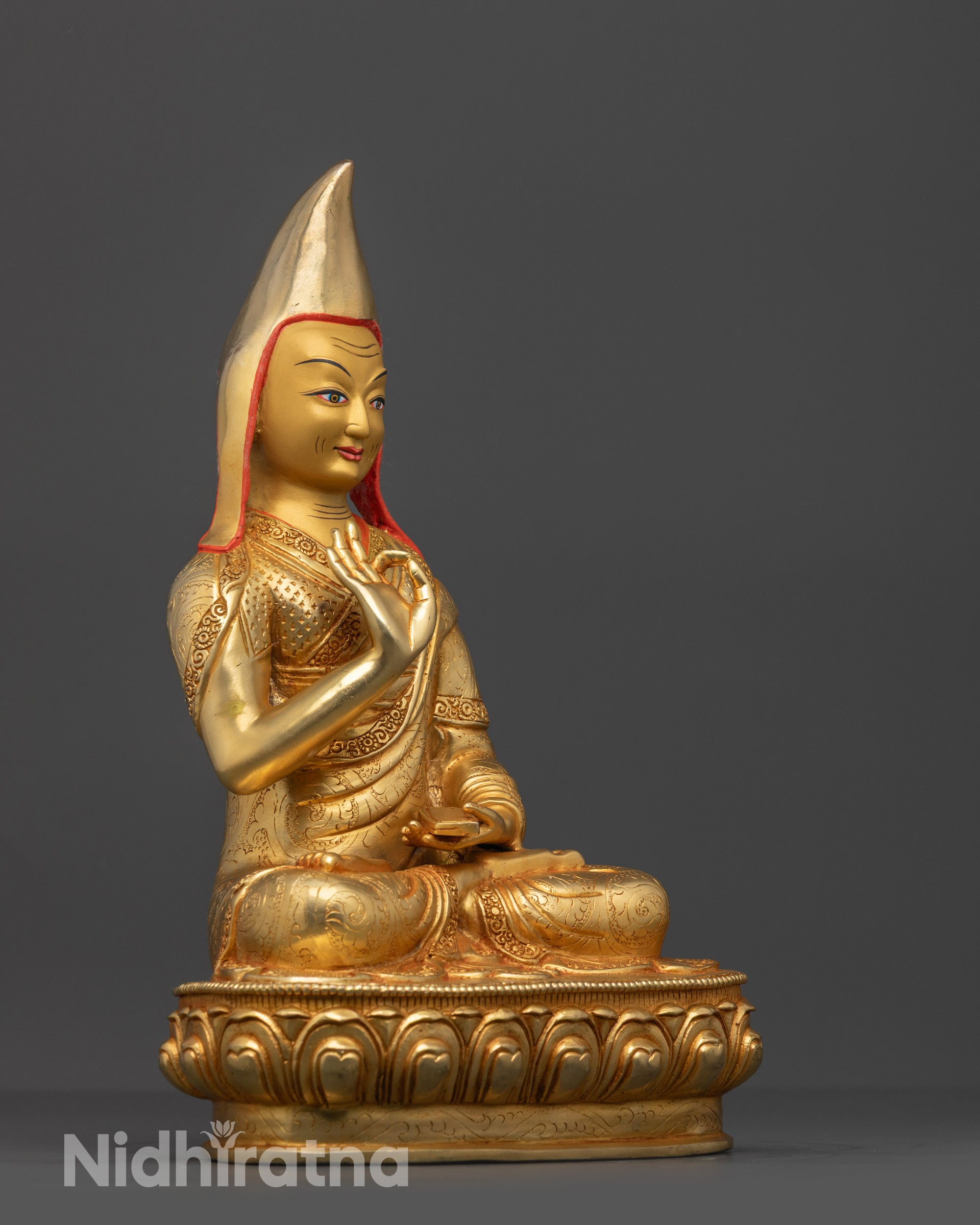 Side view Gyaltsab Je disciple statue with vitarka mudra and scripture on lotus seat
