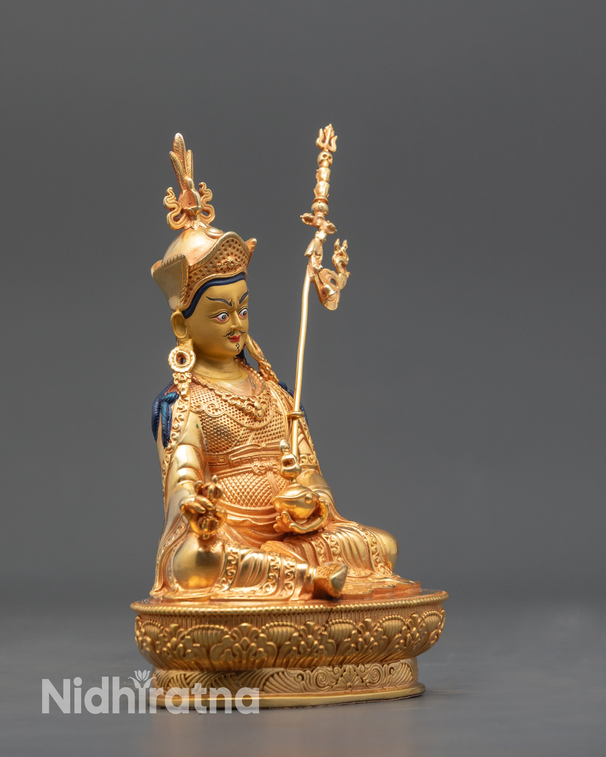 Side view Himalayan Guru Rinpoche statue highlighting gold fire-gilded body and vajra