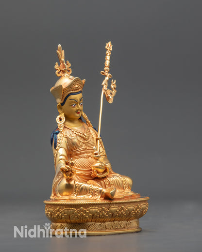 Side view Himalayan Guru Rinpoche statue highlighting gold fire-gilded body and vajra