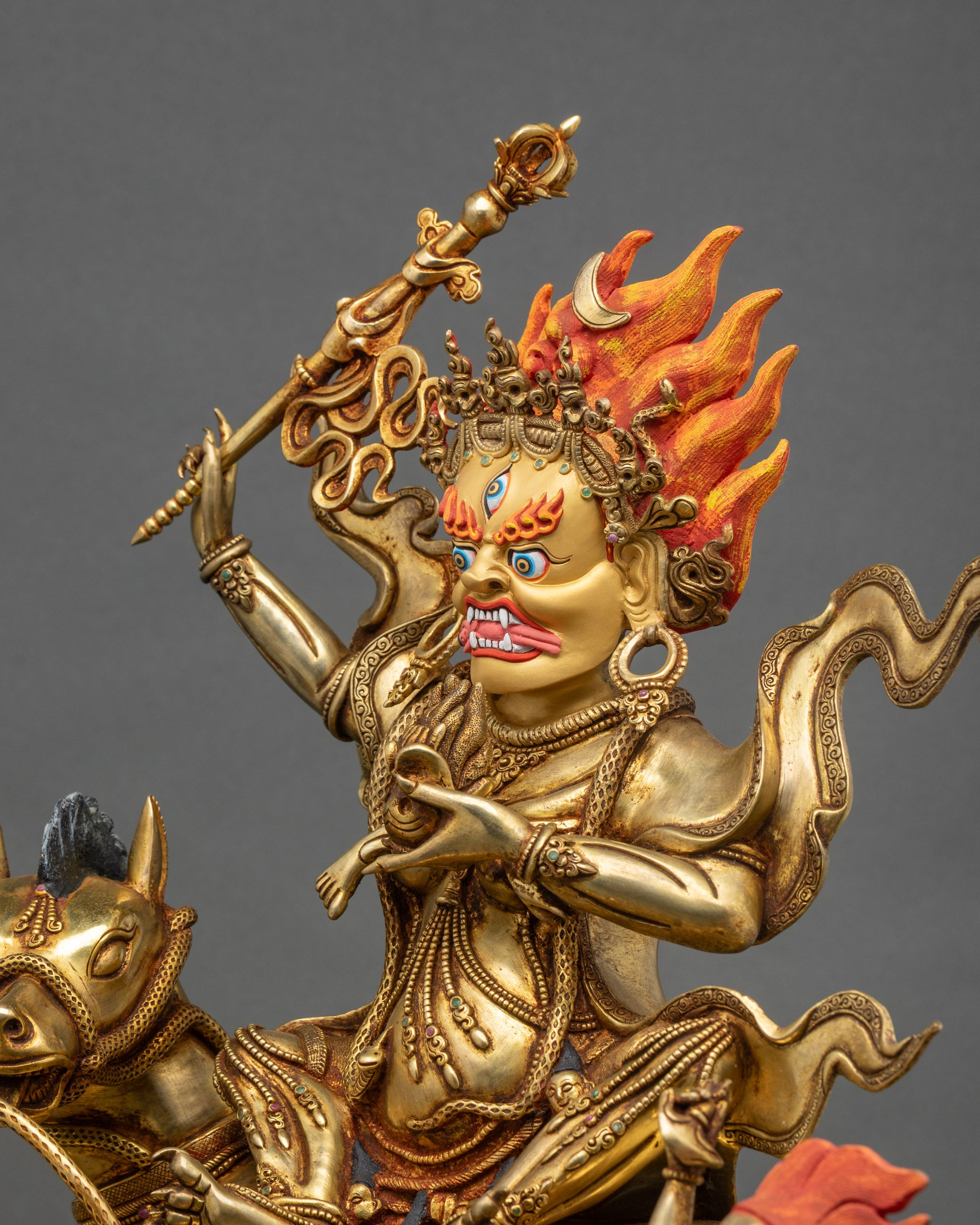 Side view Palden Lhamo statue, gold carved robes, khatvanga staff, ornate patterns, copper sculpture