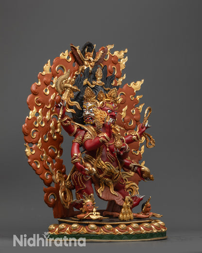 Side view Red Dzambhala sculpture with six arms holding sacred objects and lasso
