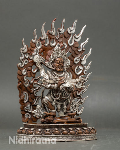 Side view Sakya Mahakala statue standing atop a human corpse holding knife and skull cup