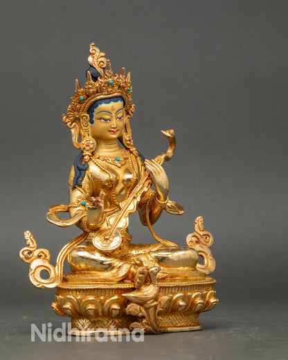Side view Saraswati statue highlighting lotus seat, flowing robes, and copper-gold