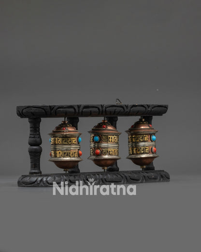 Side view Tibetan prayer wheel set showing carved dark wood frame and brass detailing