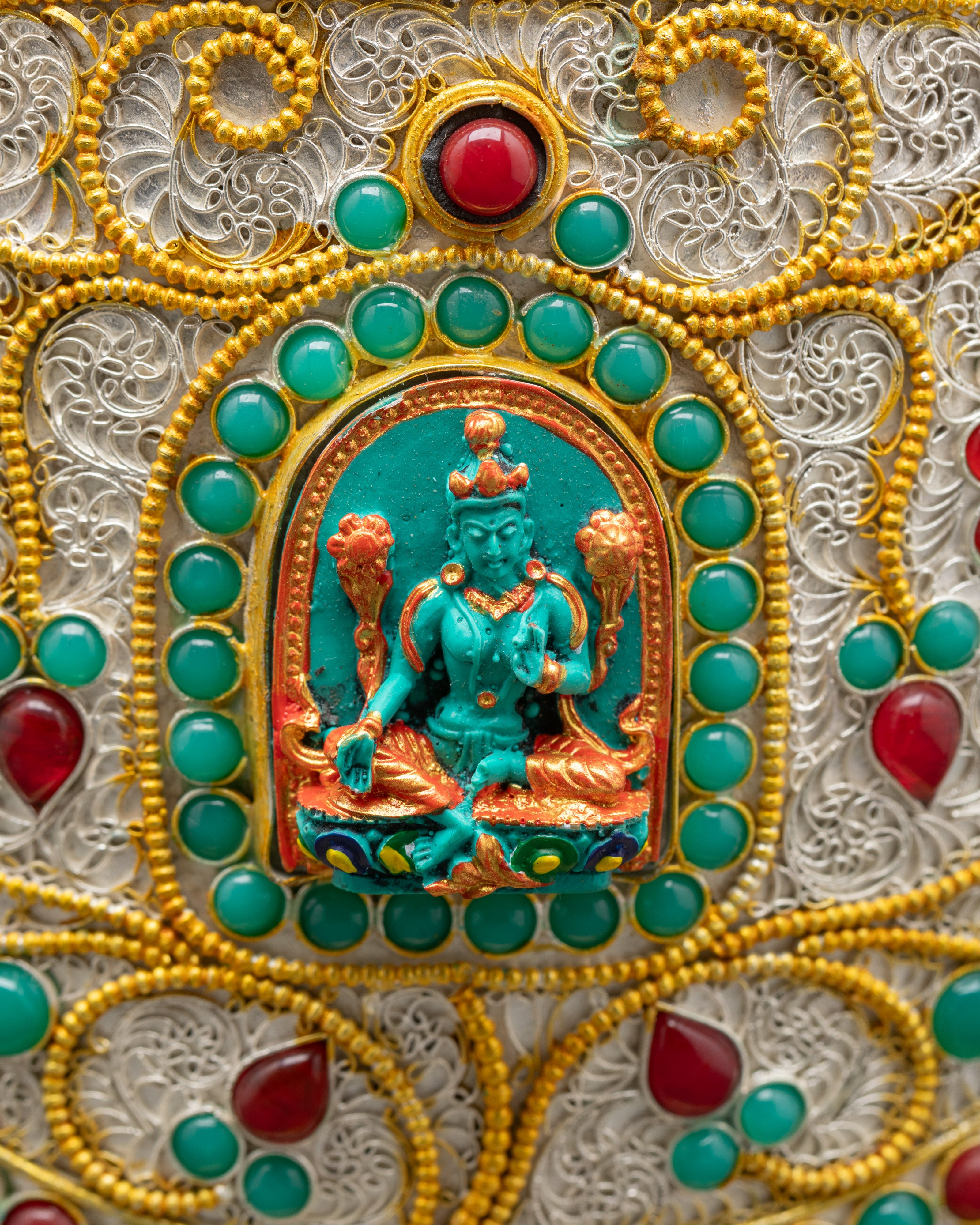 Side view Tibetan rice pot featuring carved Green Tara with turquoise and gold finish