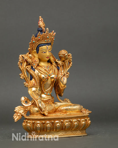 Side view White Tara statue seated on lotus throne holding stemmed lotus and Varada Mudra