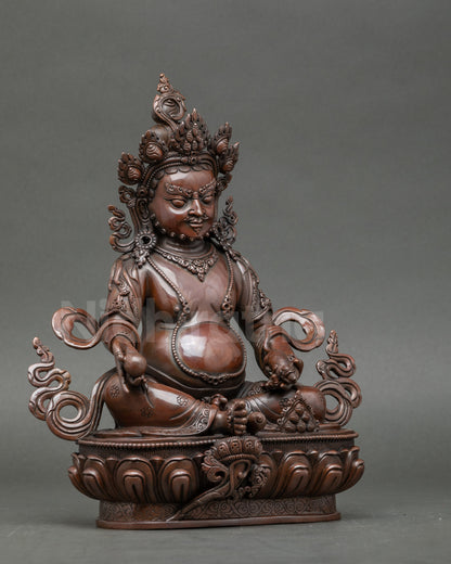 Side view copper Dzambhala statue with flowing decorative elements, symbolizing wealth and generosity