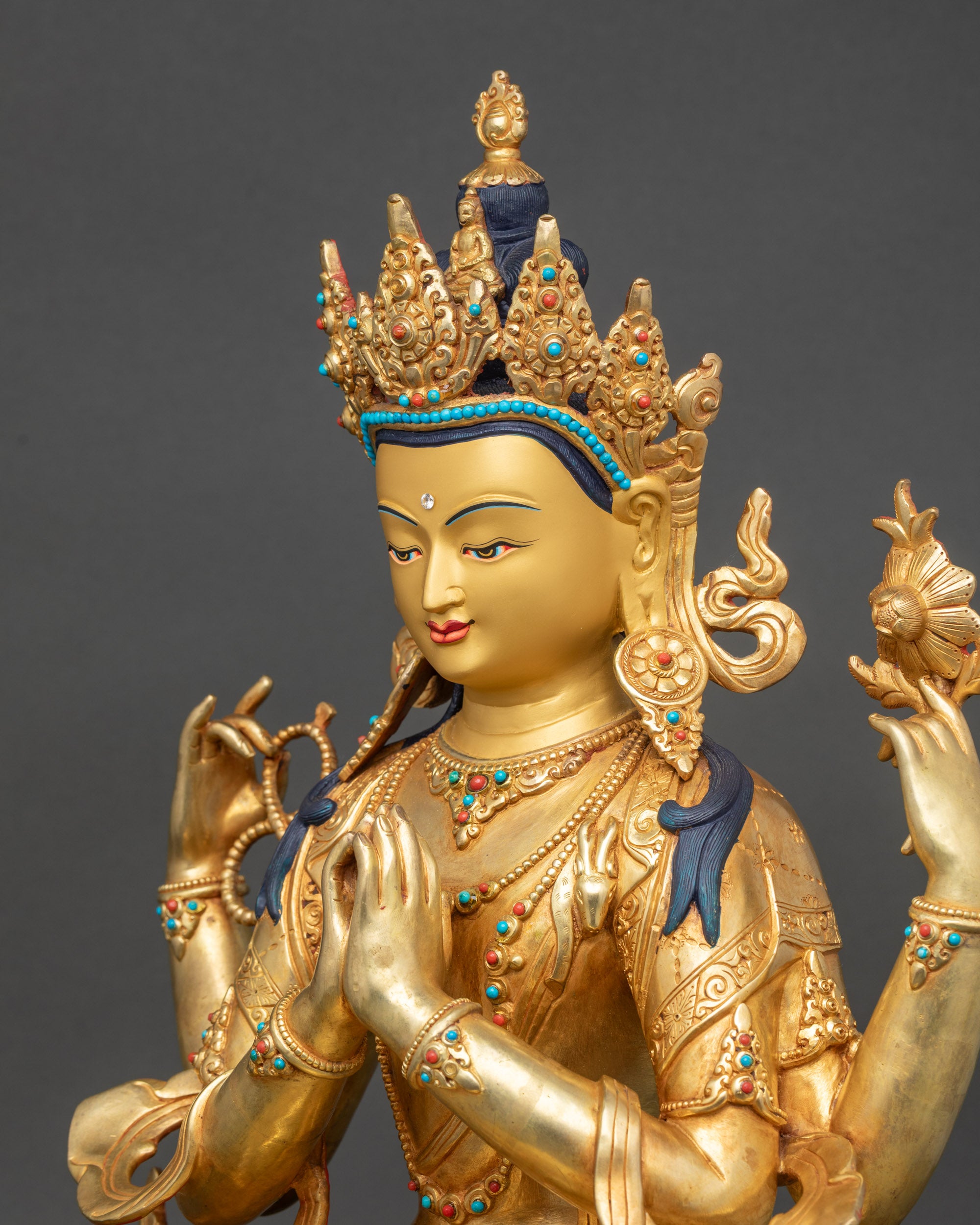 Side view of Chenrezig statue holding lotus, rosary, and heart-shaped jewel