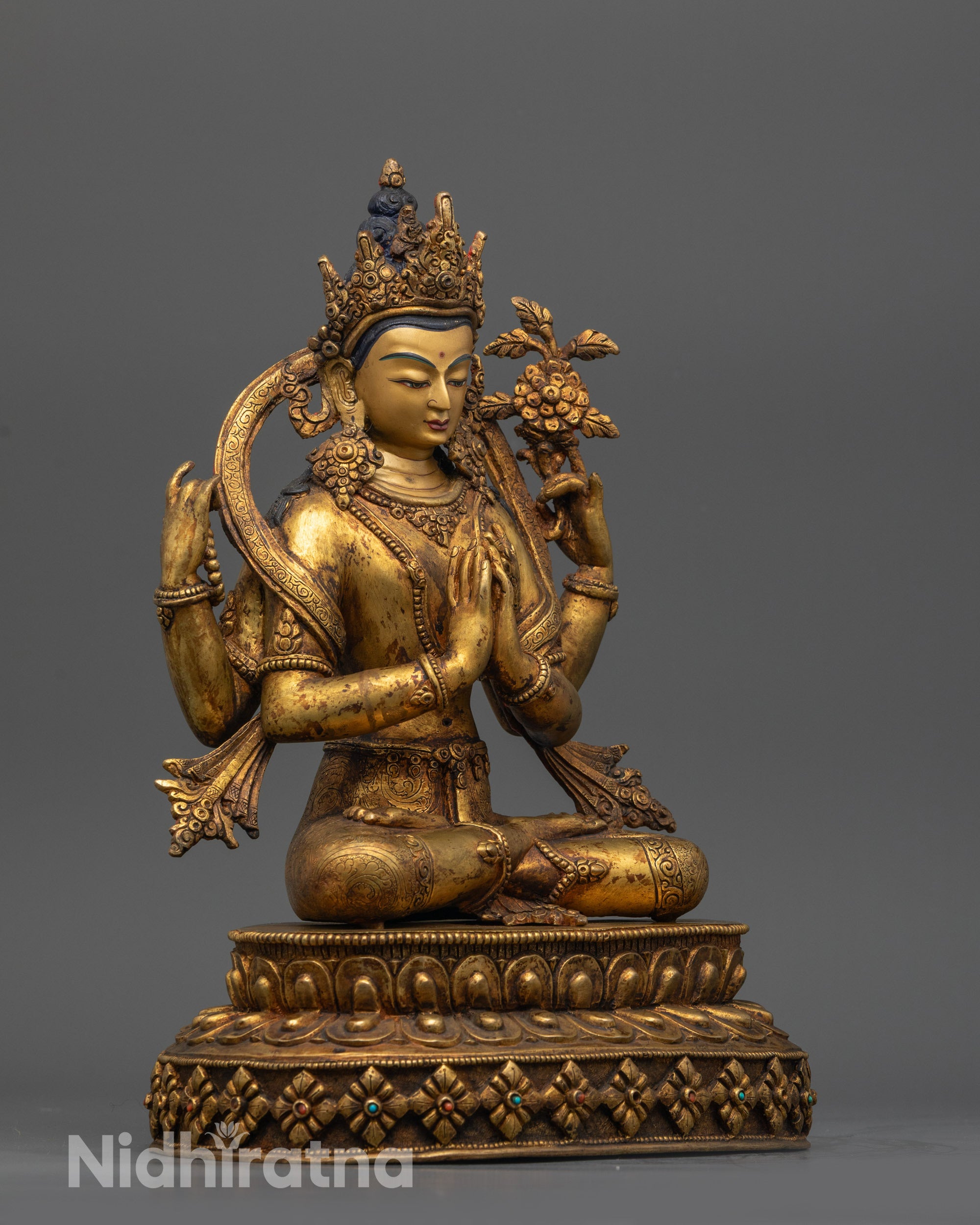 Side view of Chenrezig with four arms and swirling robes on lotus pedestal
