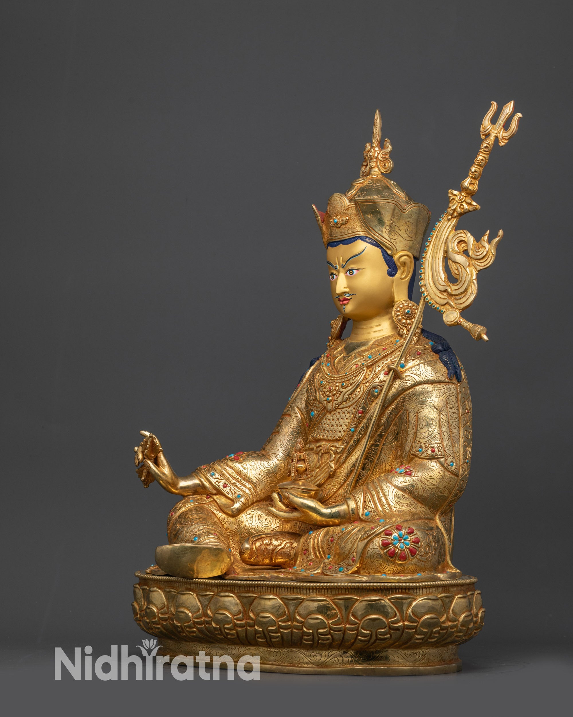 Side view of Divine Padmasambhava statue seated on lotus with gold-gilded face
