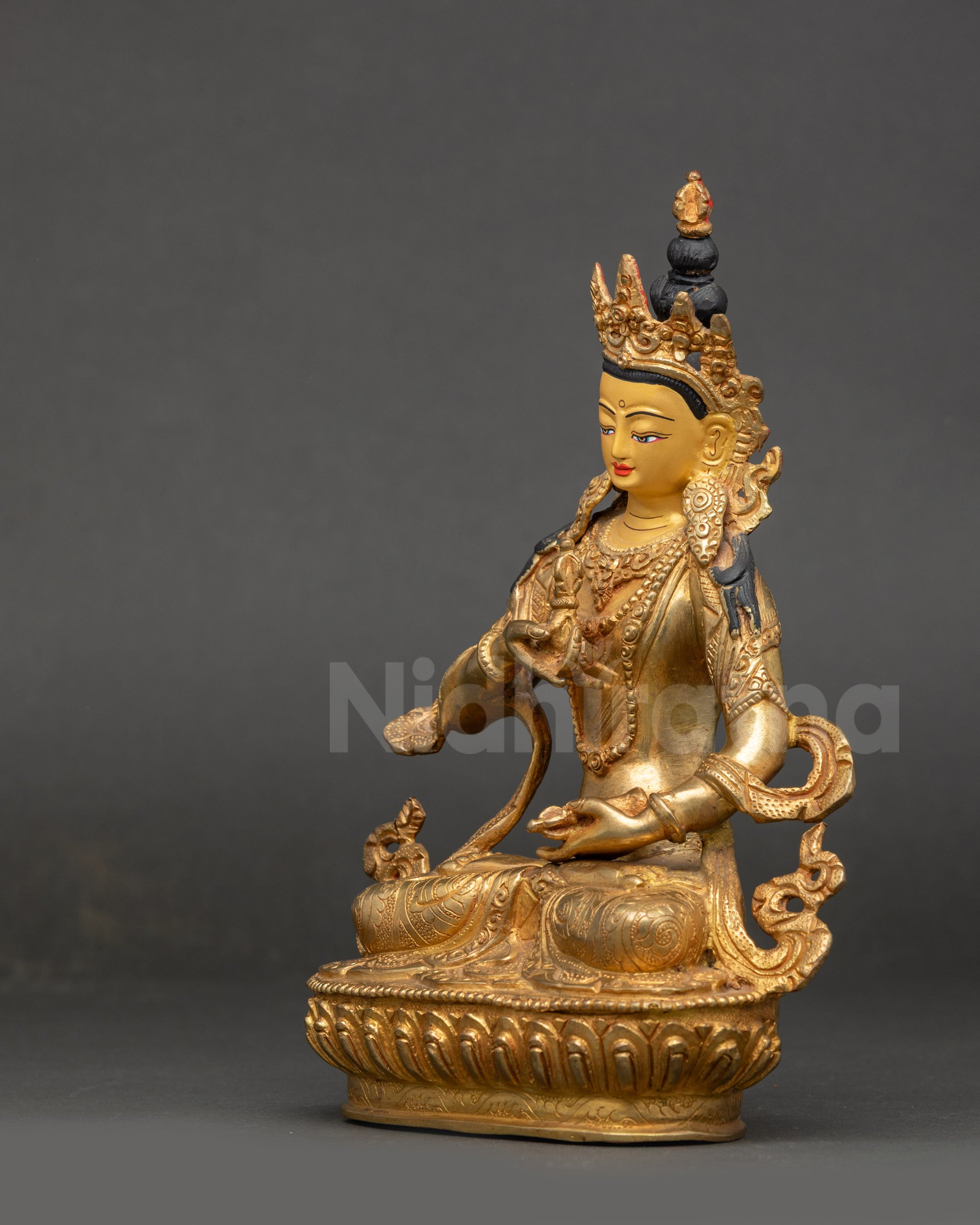 Side view of Dorje Sempa statue holding vajra and bell on lotus seat