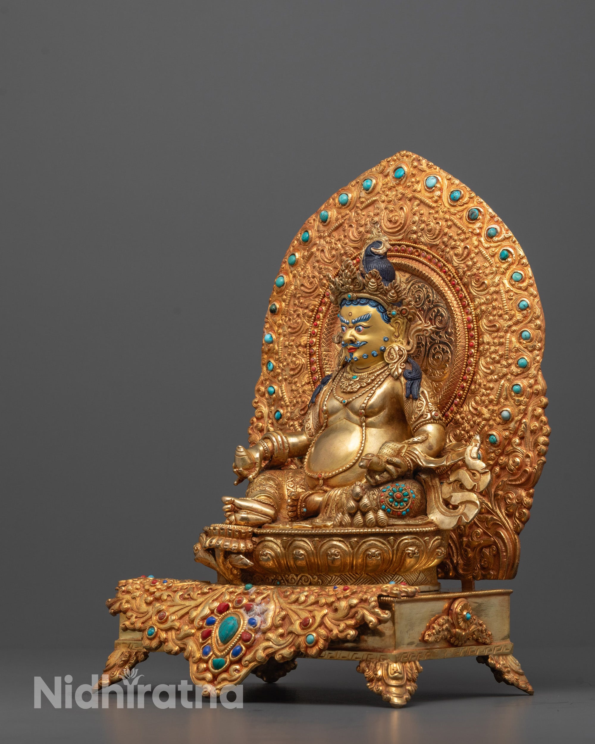 Side view of Dzambhala Statue displaying vibrant semi-precious stones and fire-gilded