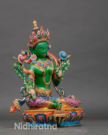 Side view of Green Tara idol in active protection pose, multi-colored lotus pedestal, gold-plated finish
