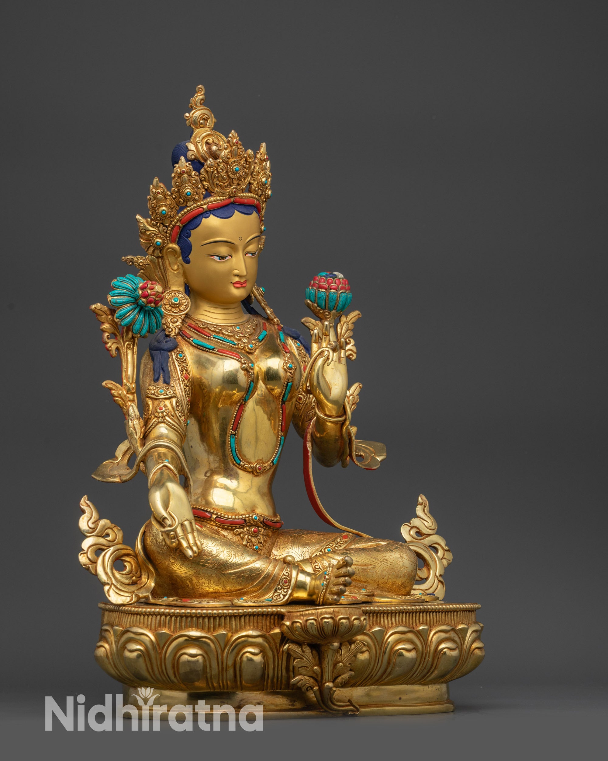 Side view of Green Tara statue on lotus seat with Utpala flower and royal ease pose