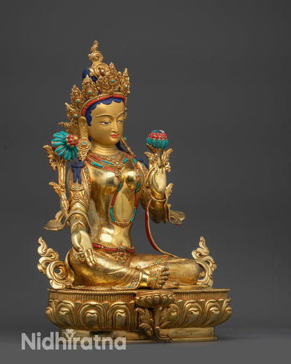 Side view of Green Tara statue on lotus seat with Utpala flower and royal ease pose