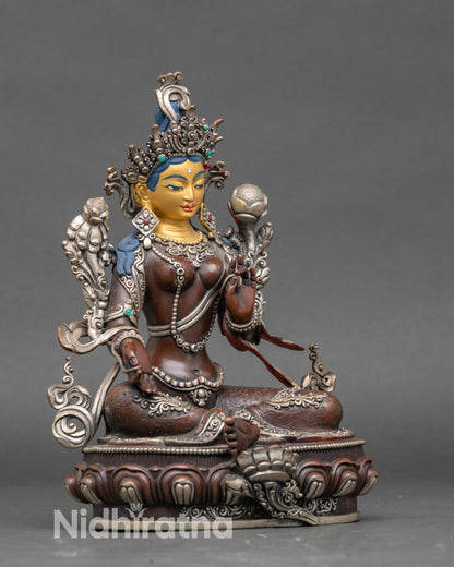 Side view of Green Tara statue showing intricate floral motifs and flowing celestial robes