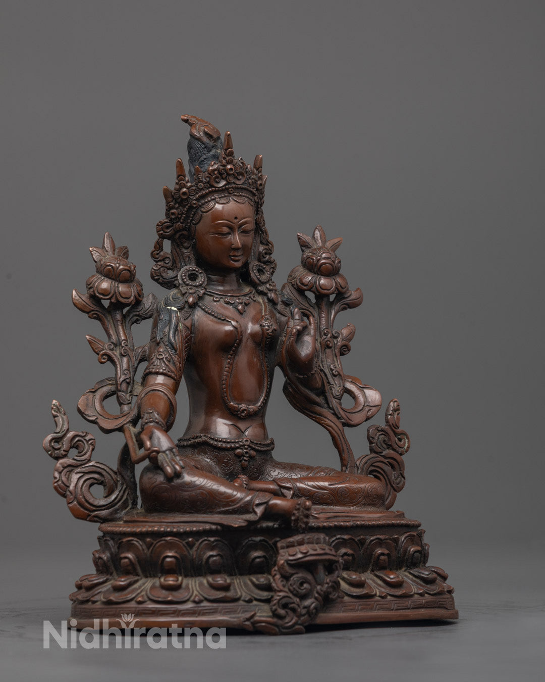 Side view of Green Tara statue with oxidized copper finish seated gracefully