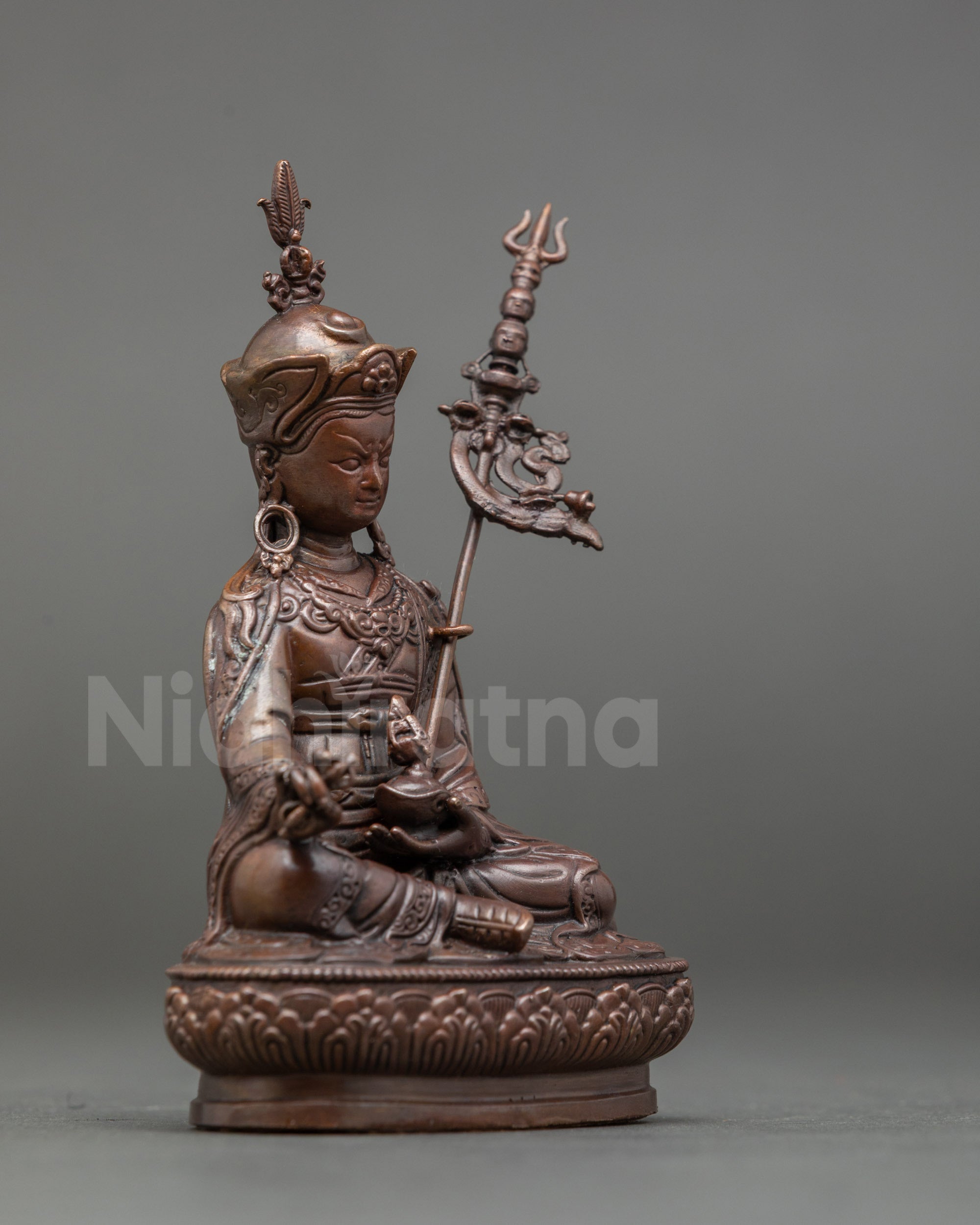 Side view of Guru Padmasambhava Sculpture highlighting khatvanga staff and lotus pedestal