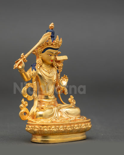 Side view of Manjushri statue showing flaming sword and lotus flower in hands