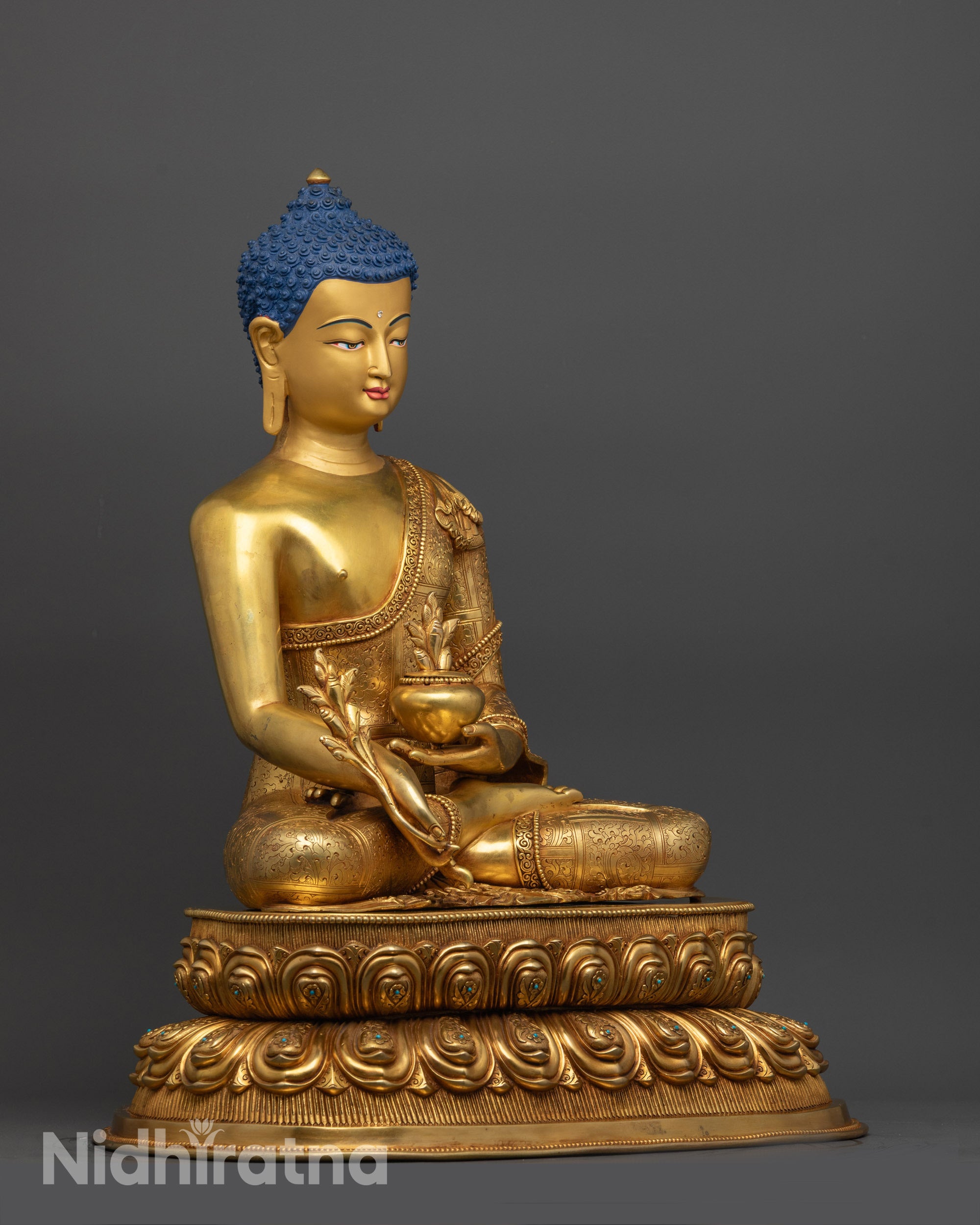 Side view of Medicine Buddha copper statue with intricate robe patterns and gemstones