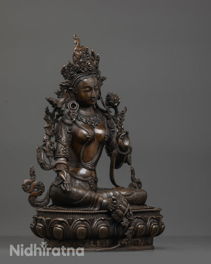 Side view of Oxidized Green Tara seated in royal ease with swirling robe and crown