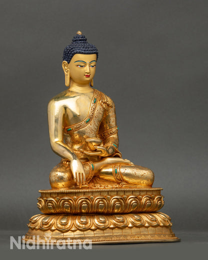 Side view of Shakyamuni Buddha statue seated on double lotus with monk’s bowl, copper and gold details