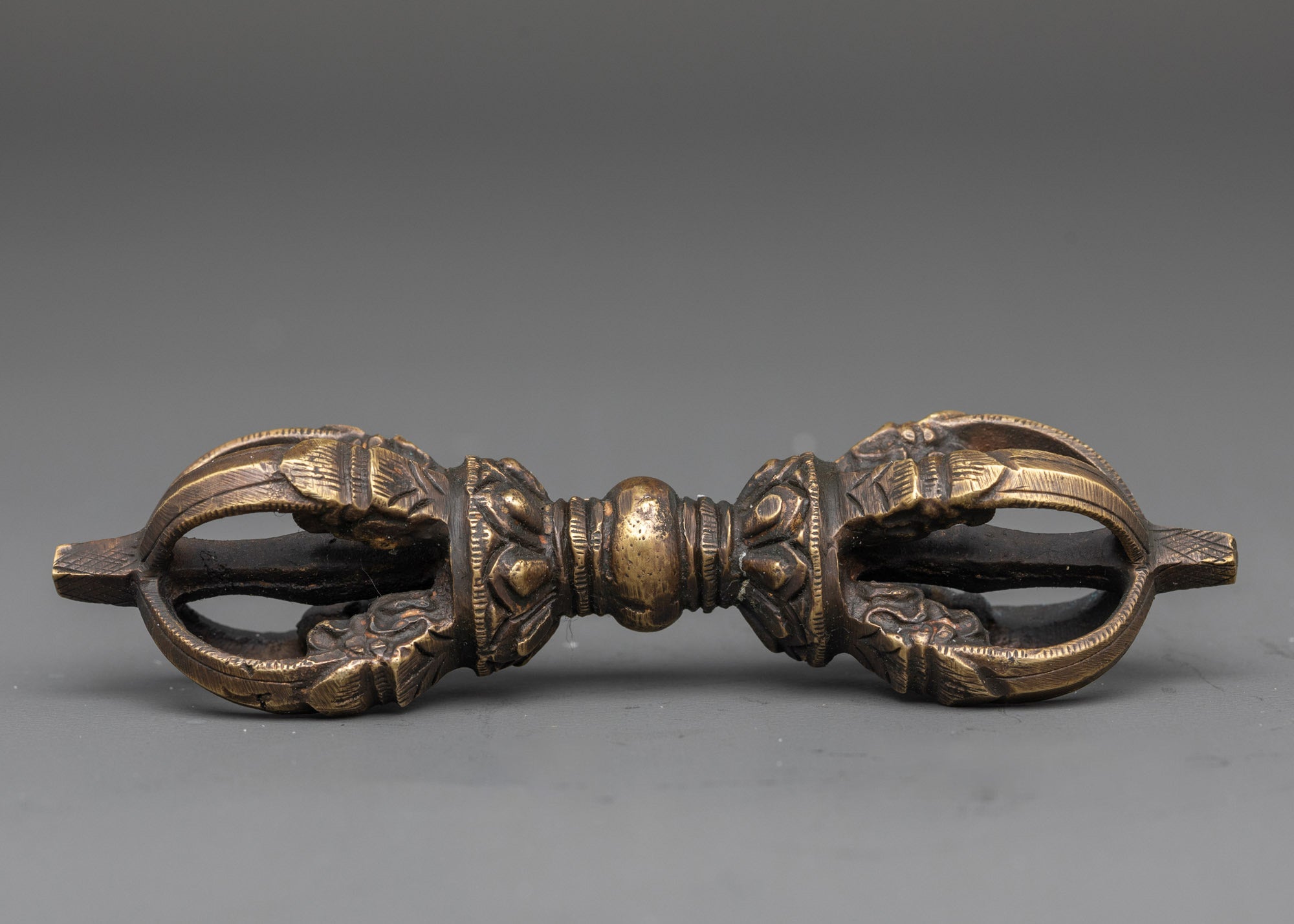 Side view of bronze vajra with detailed carvings for Vajrayana practice