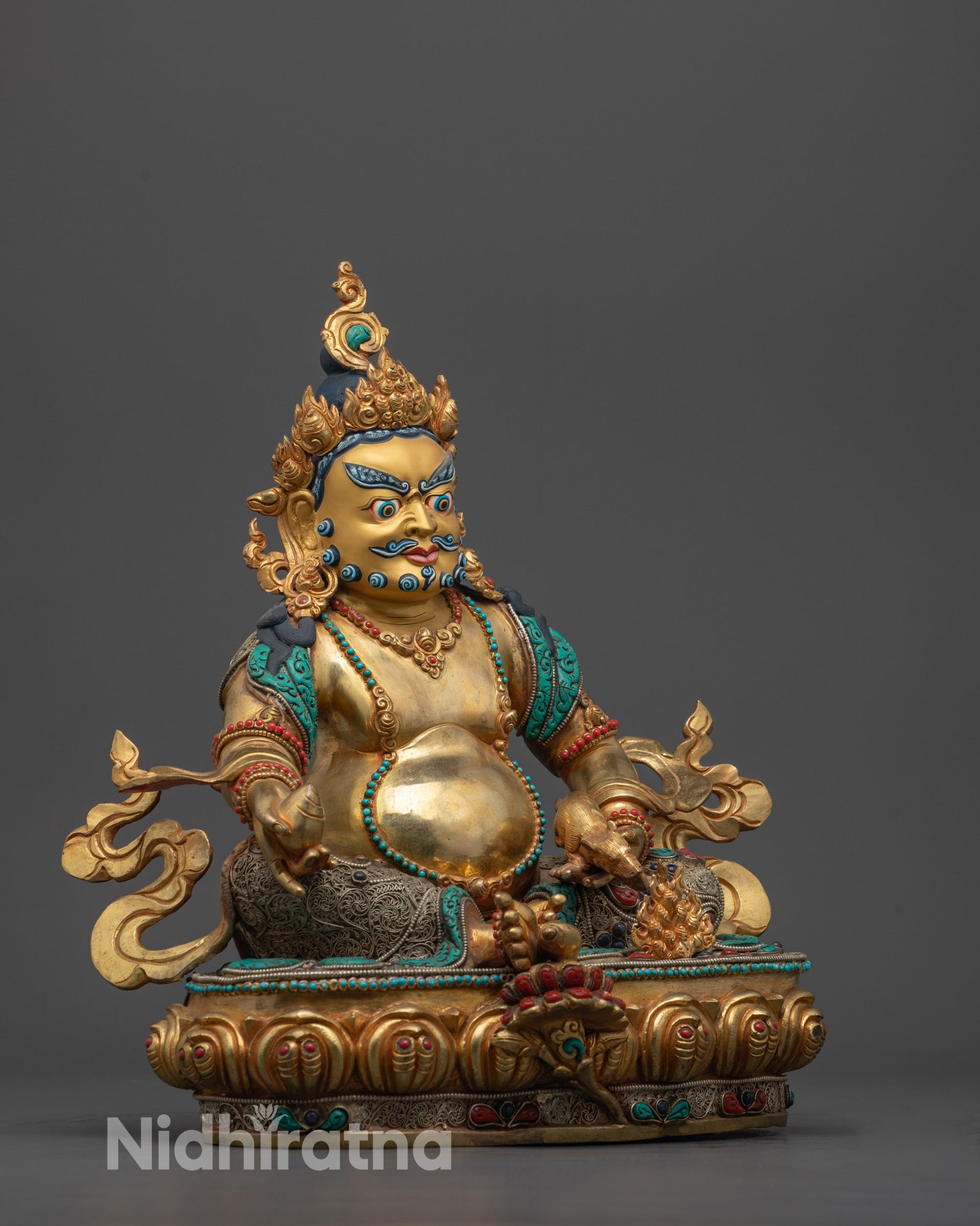Side view of copper-based Dzambhala Statue with radiant gold gilding and gemstone inlays