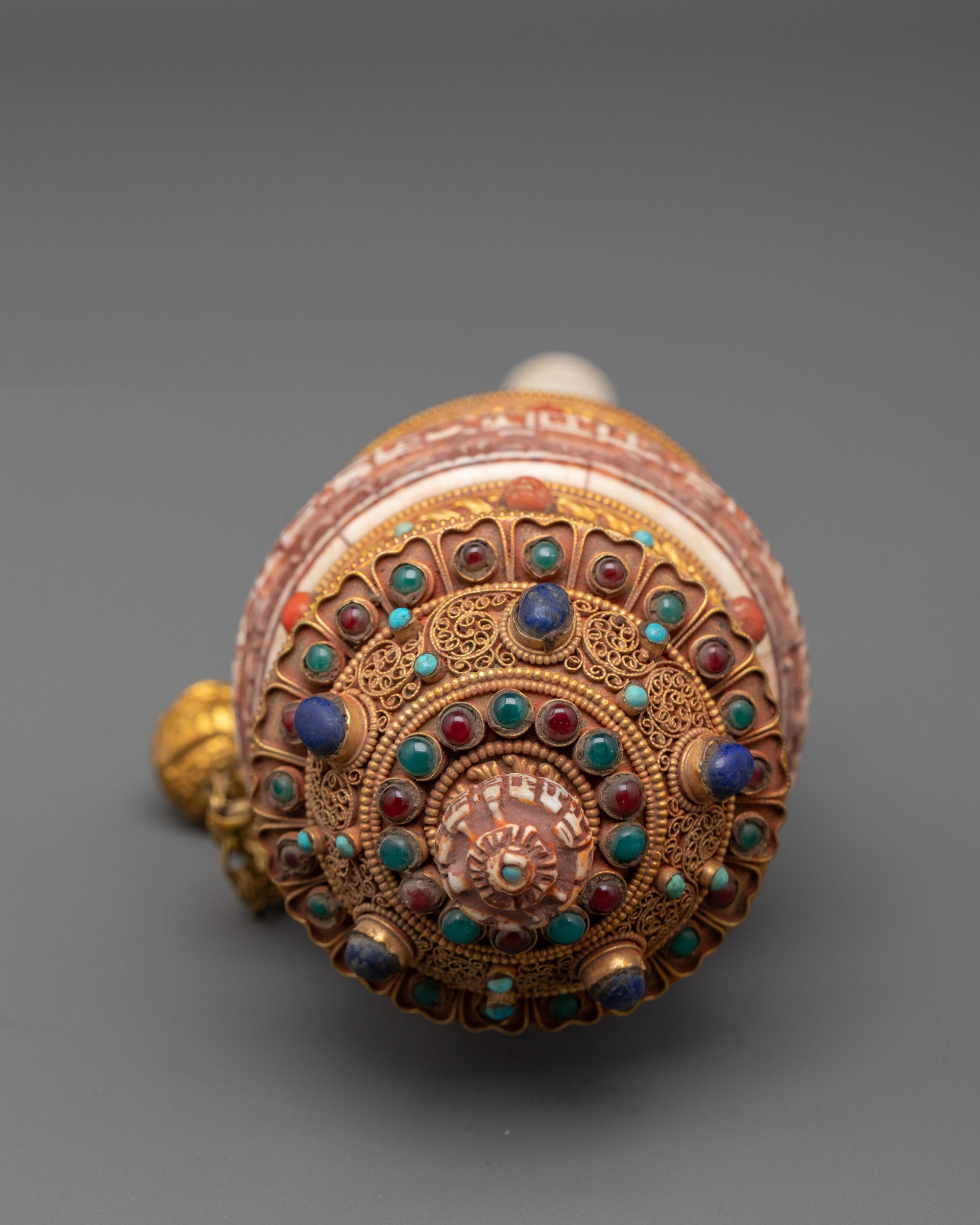 Side view of copper mantra prayer wheel adorned with gold filigree designs and sacred mantra