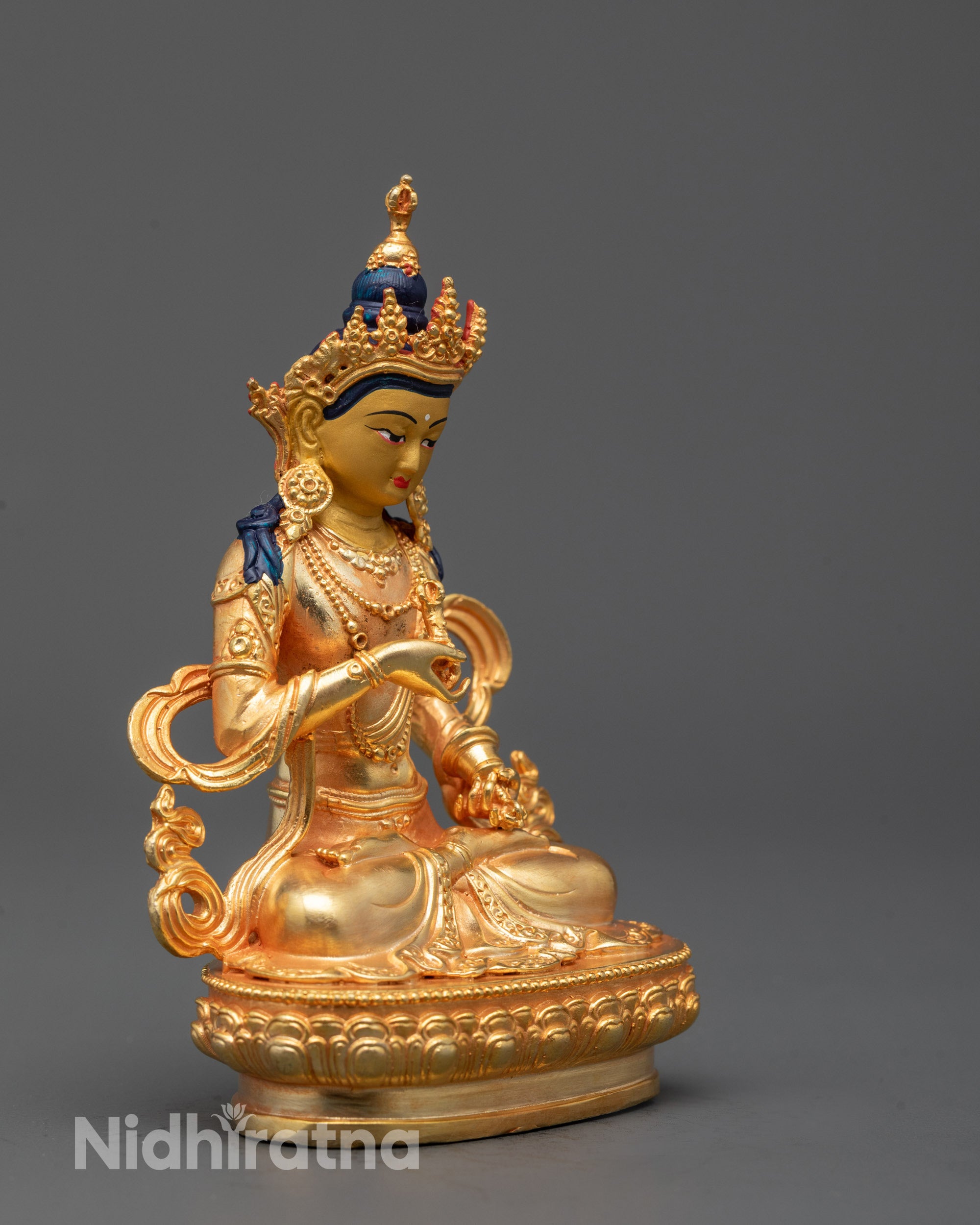 Side view of electroplated Vajrasattva statue holding vajra and bell with flowing robes