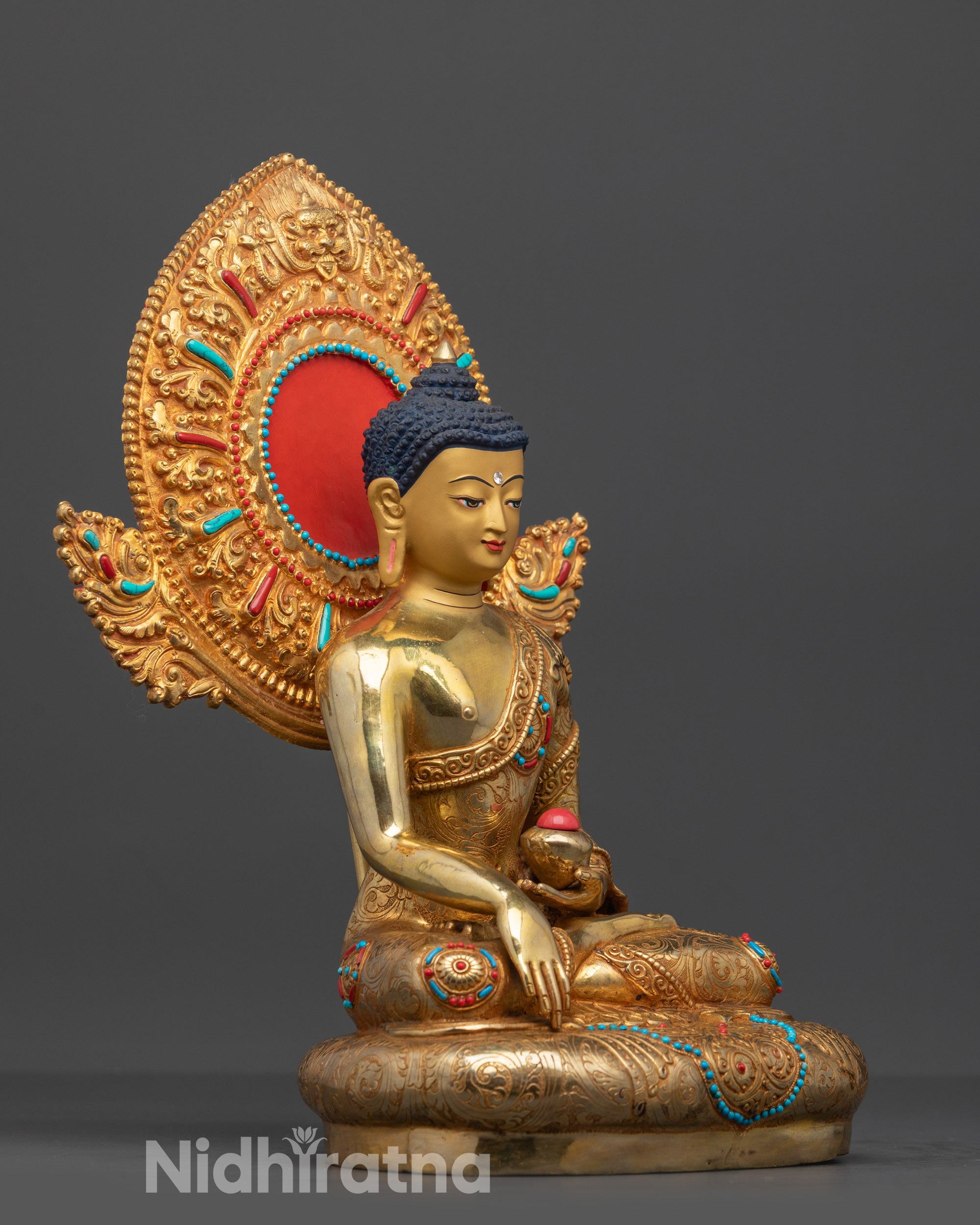 Side view of gold fire-gilded Buddha Shakyamuni statue seated in lotus pose