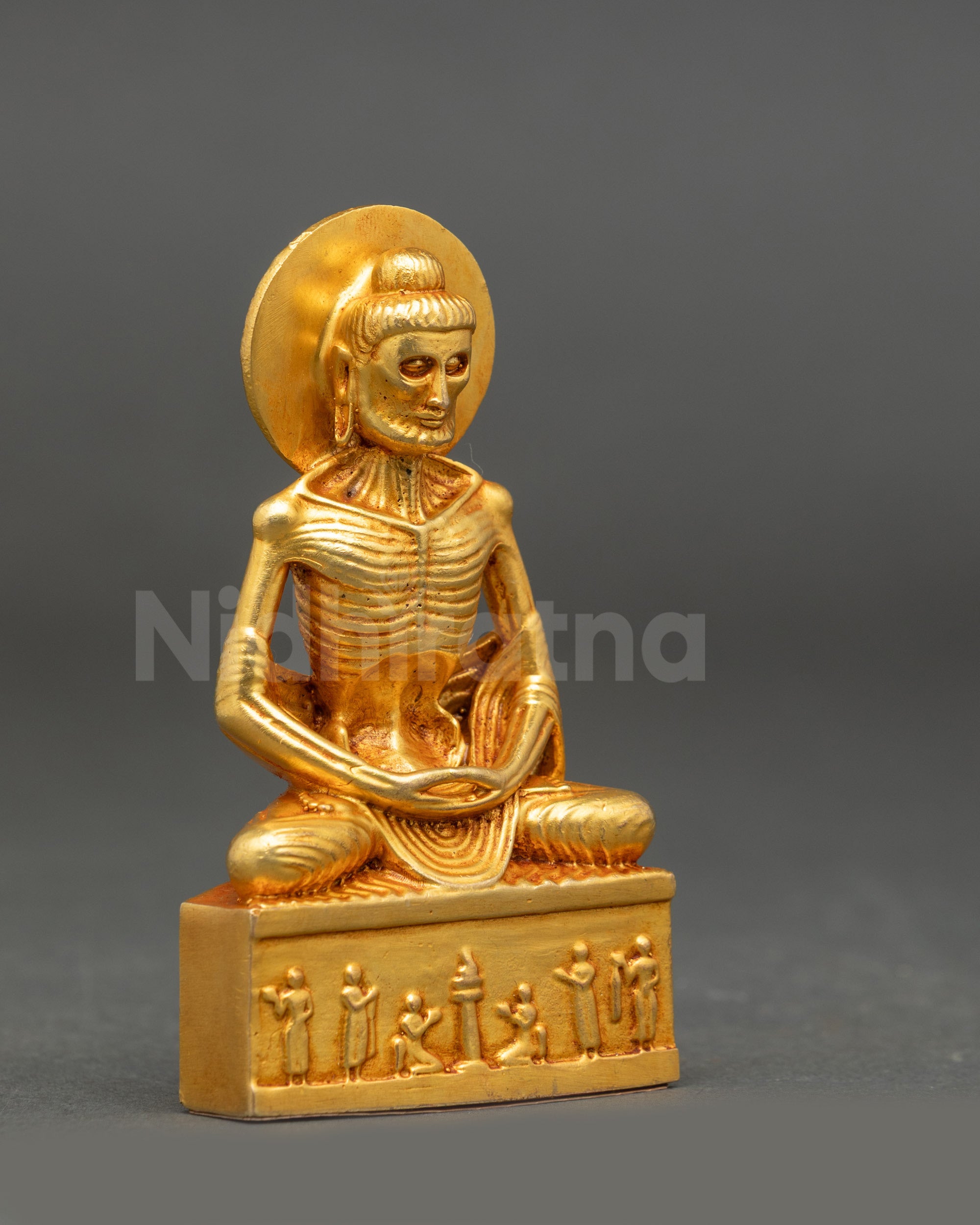 Side view of gold fire-gilded Fasting Buddha statue highlighting ascetic emaciated form