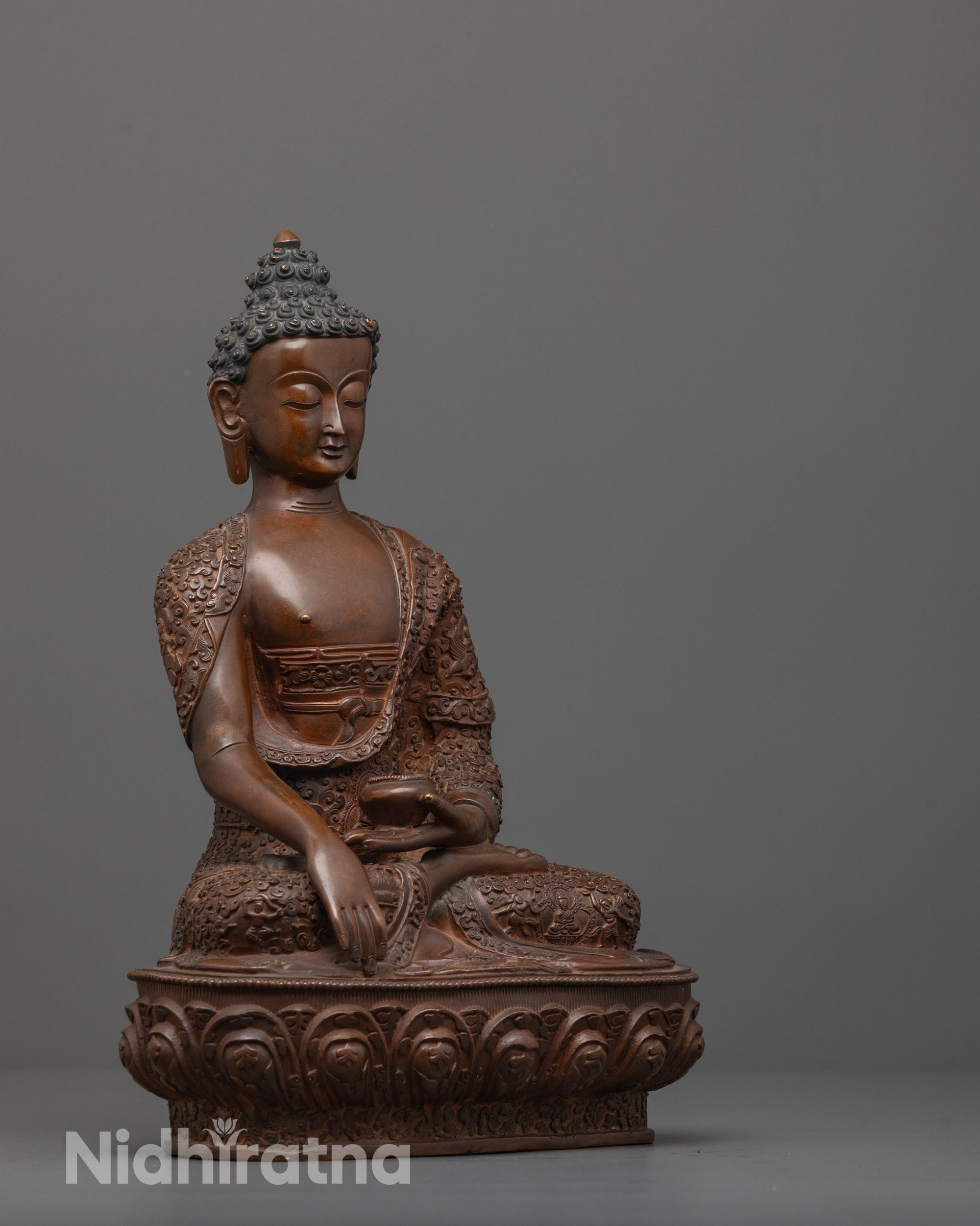 Side view of handcrafted Buddha statue highlighting lotus seat with carved divine figures.