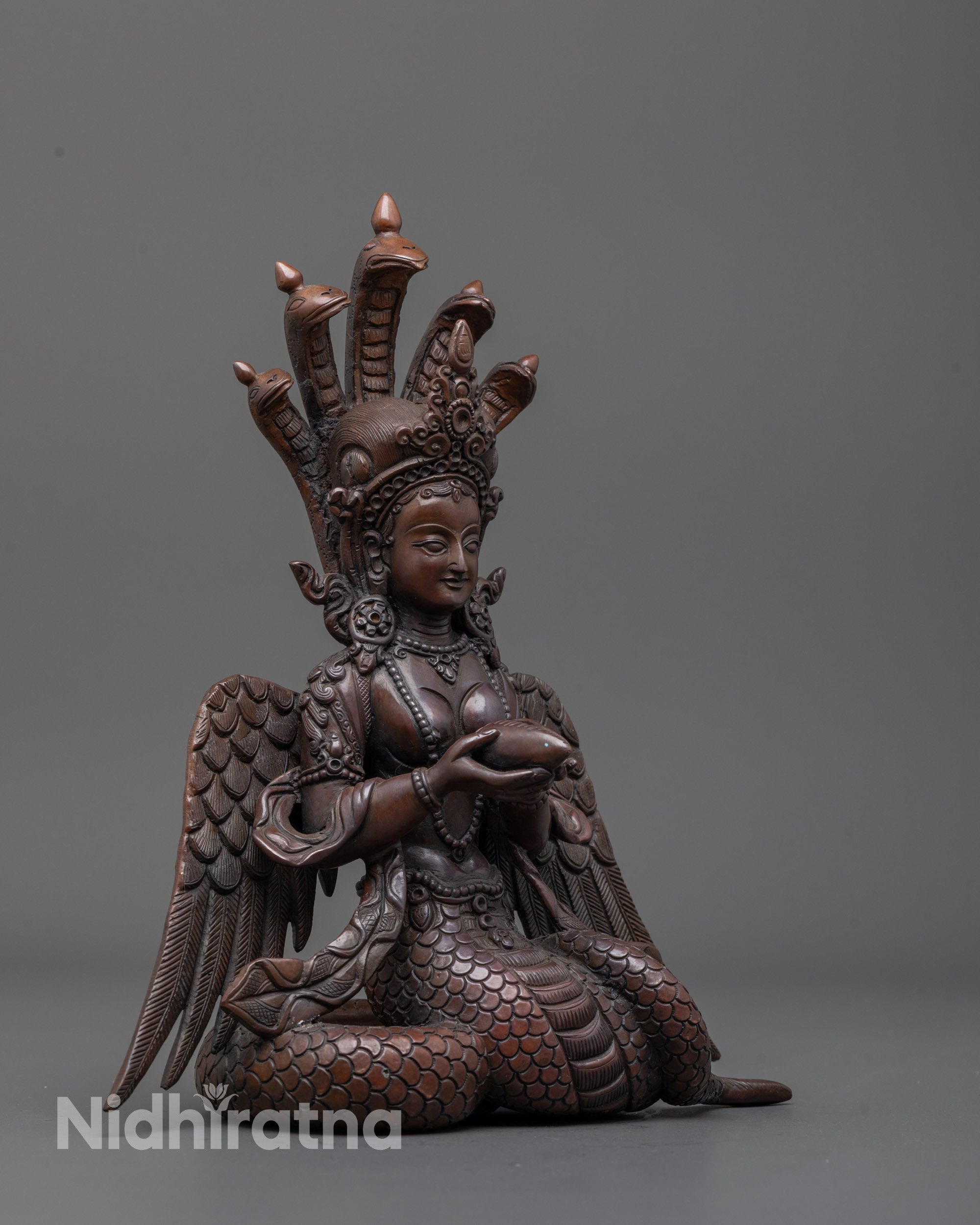 Side view of serpent goddess statue displaying intricate wings and elegant body curves