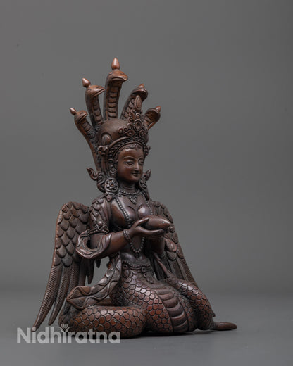 Side view of serpent goddess statue displaying intricate wings and elegant body curves