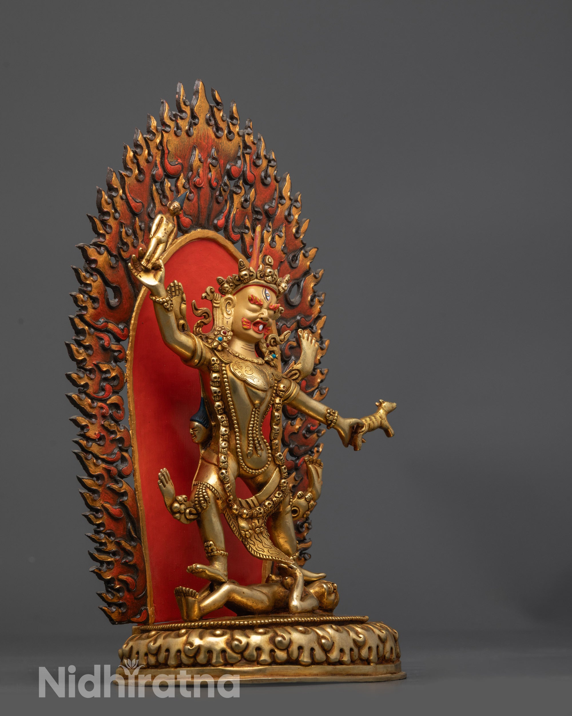 Side view of wrathful Ekajati statue crushing entity atop lotus seat with radiant halo
